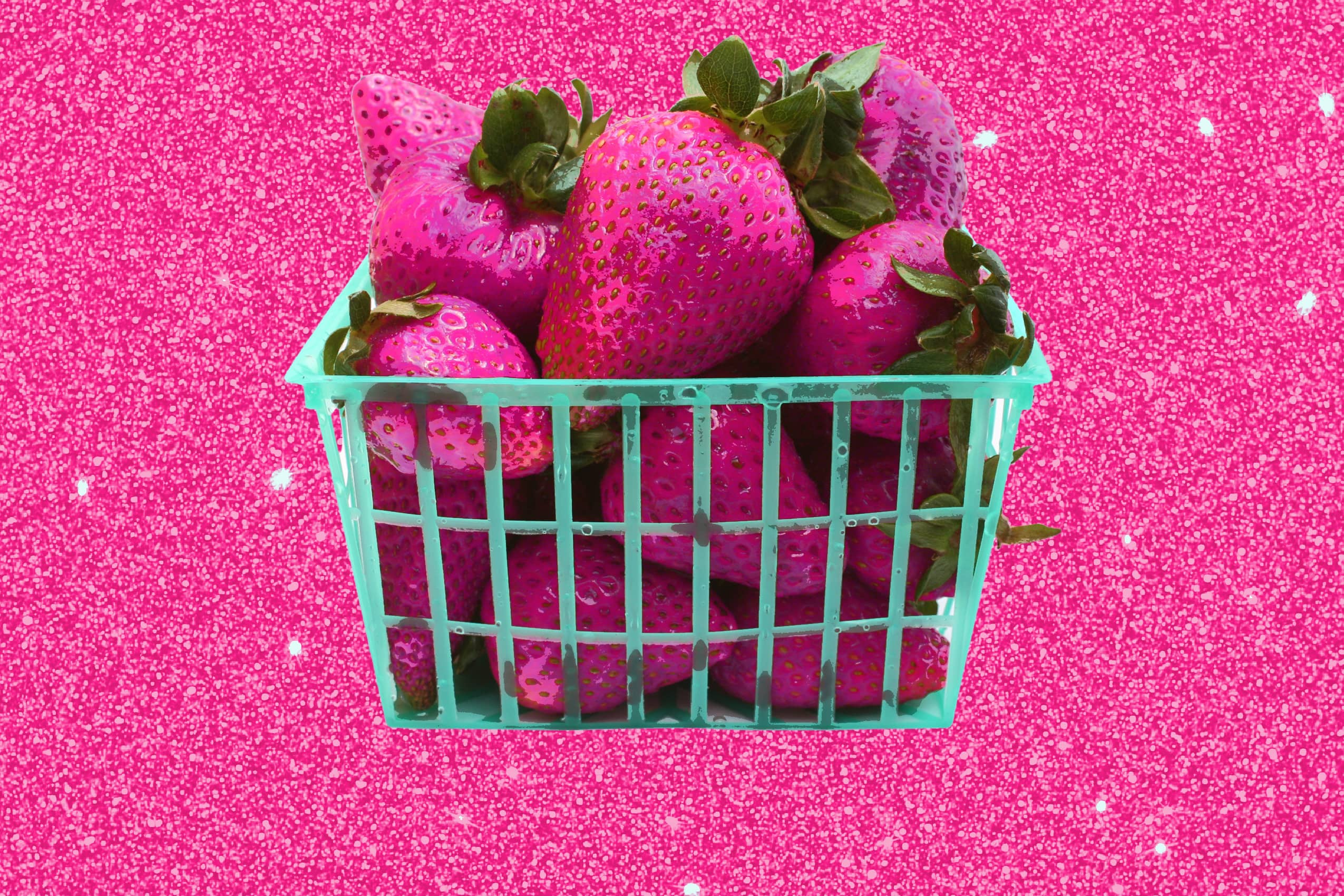 pink glitter background with a green basket of red strawberries.